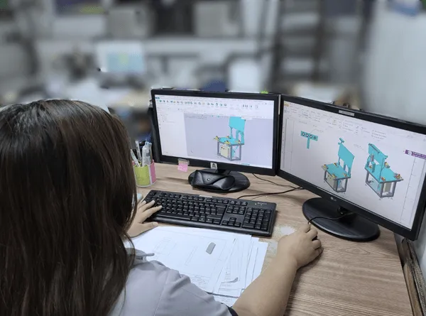Engineer reviewing 3D CAD models of a custom machine design on dual monitors